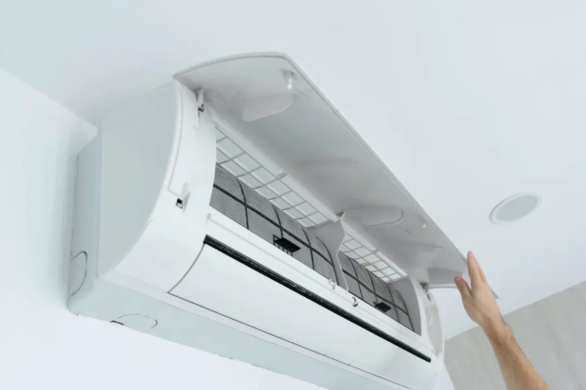 Hand opening the cover of a wall-mounted ductless air conditioner
